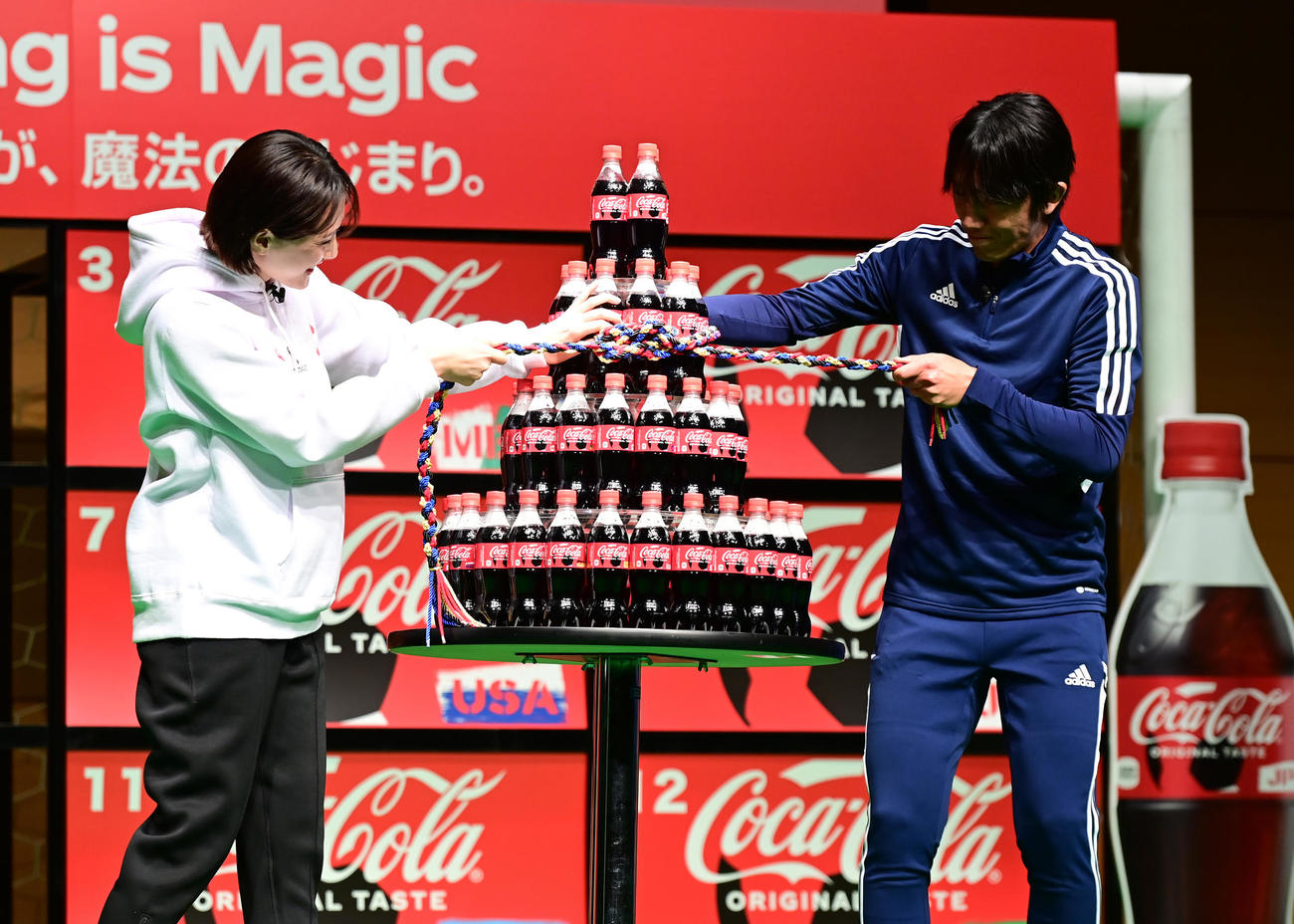 「コカ・コーラ」FIFAワールドカップ開催国ボトル発売記念イベントでボトルを積み上げたタワーをミサンガで縛る綾瀬はるか（左）と元サッカー日本代表の中村氏（撮影・小沢裕）