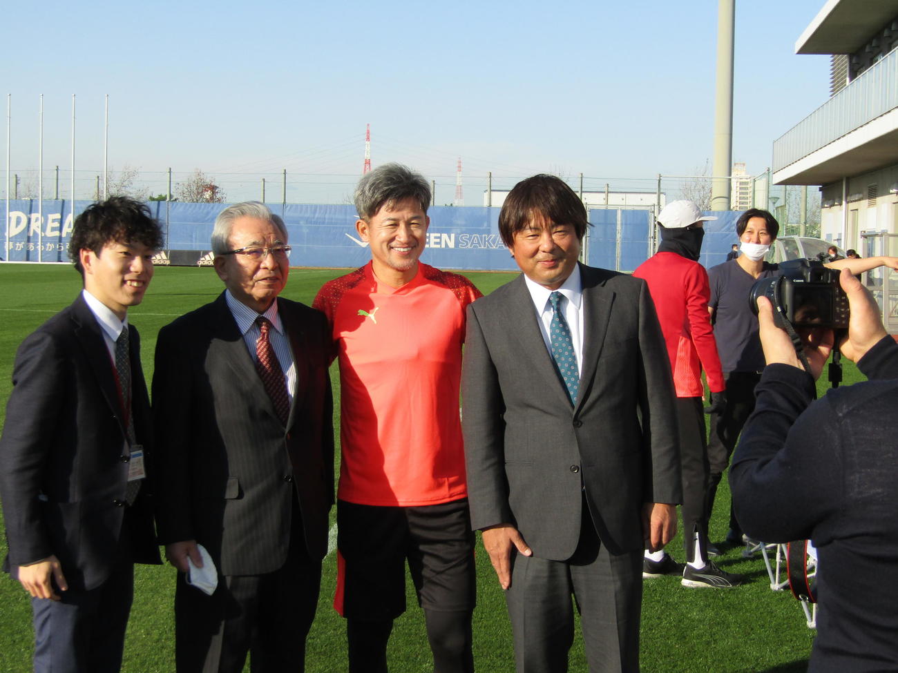 自主トレ開始前にカズ（中央）は関係者と記念撮影