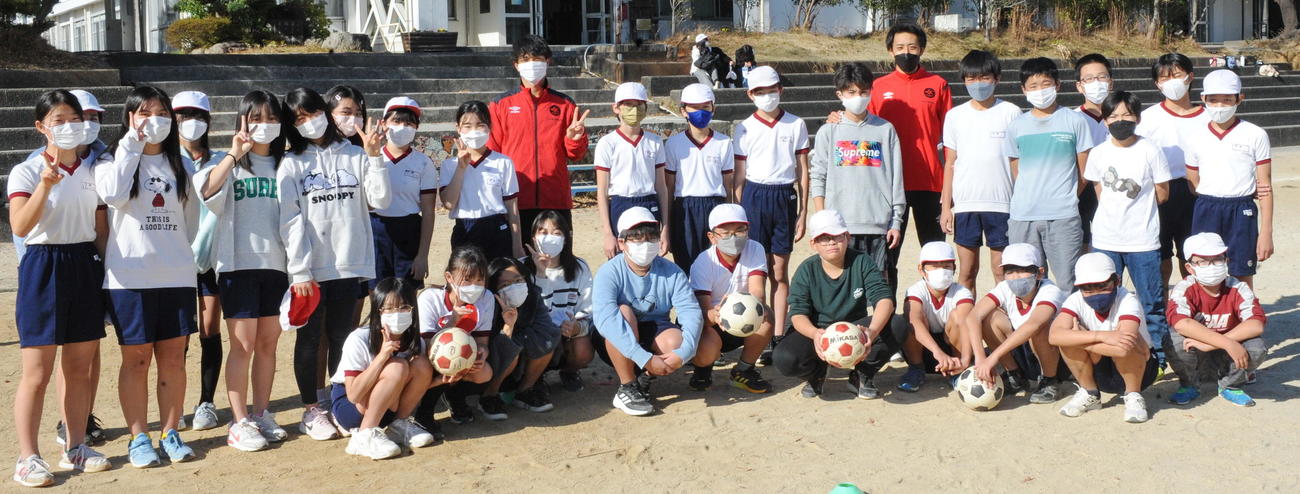 ホンダFCの選手2人と記念撮影に納まる浜松城北小6年2組の児童たち　