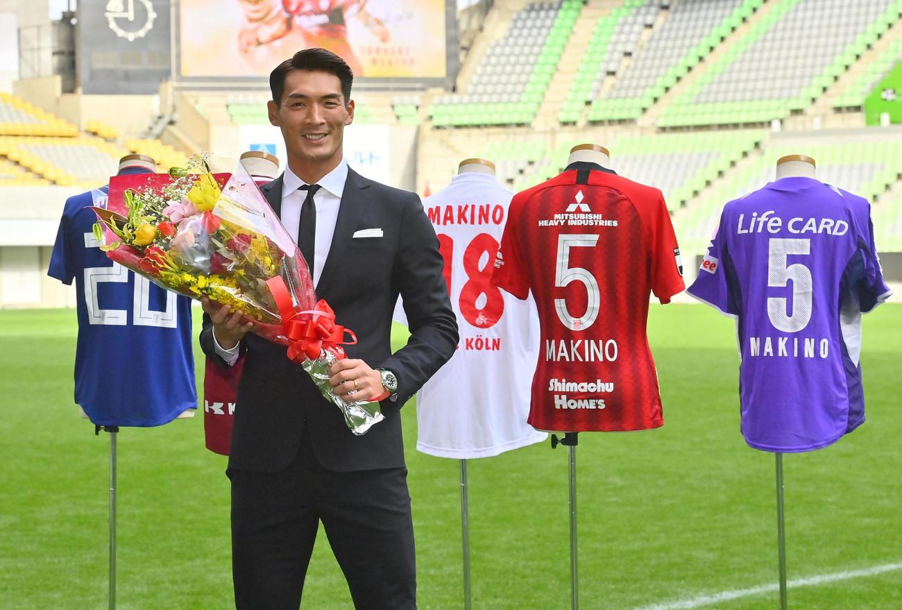 引退会見後、過去に所属したユニホームを背に写真に納まる神戸槙野（撮影・和賀正仁）