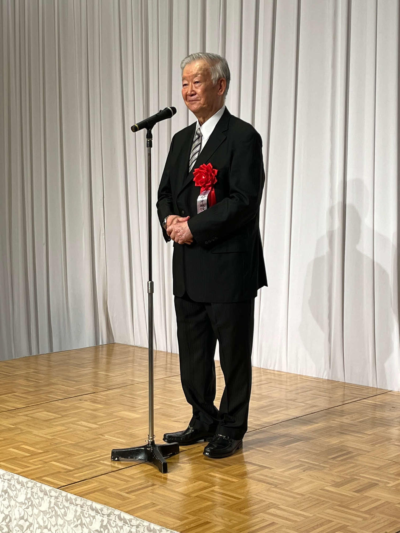 来日50周年パーティーで壇上からあいさつするセルジオ越後氏