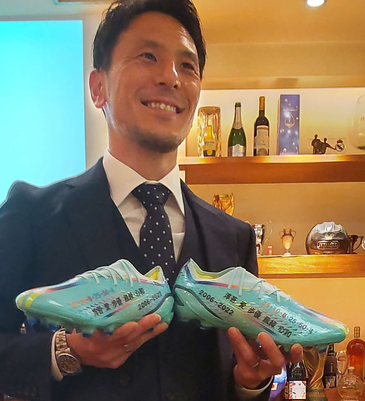 引退会見で、ホペイロの松浦紀典さんから届いた特別なスパイクを手に笑顔をみせる藤本淳吾