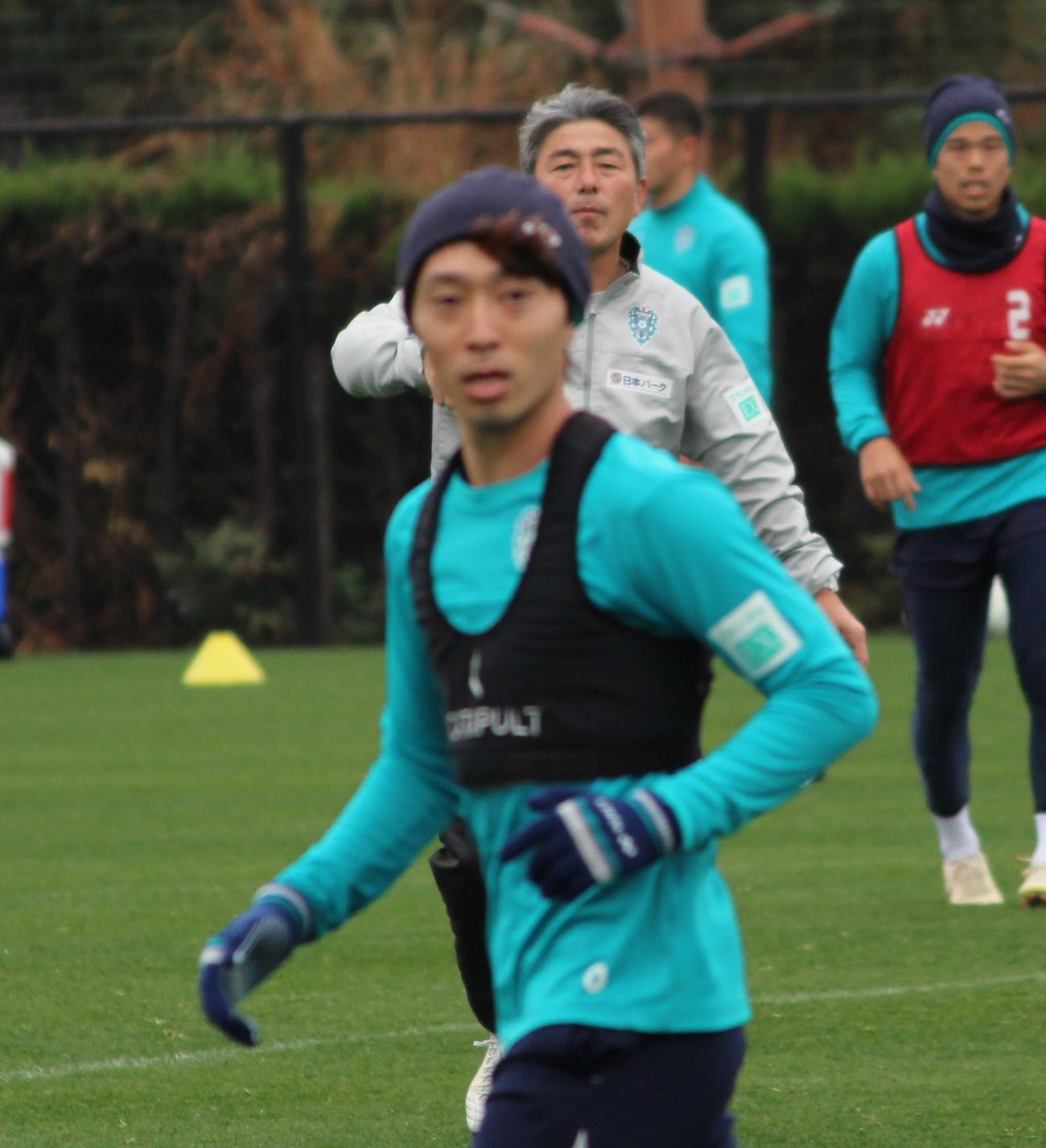 福岡の練習で、MF中村駿（前方）ら選手の動きを見守る長谷部茂利監督（撮影・菊川光一）