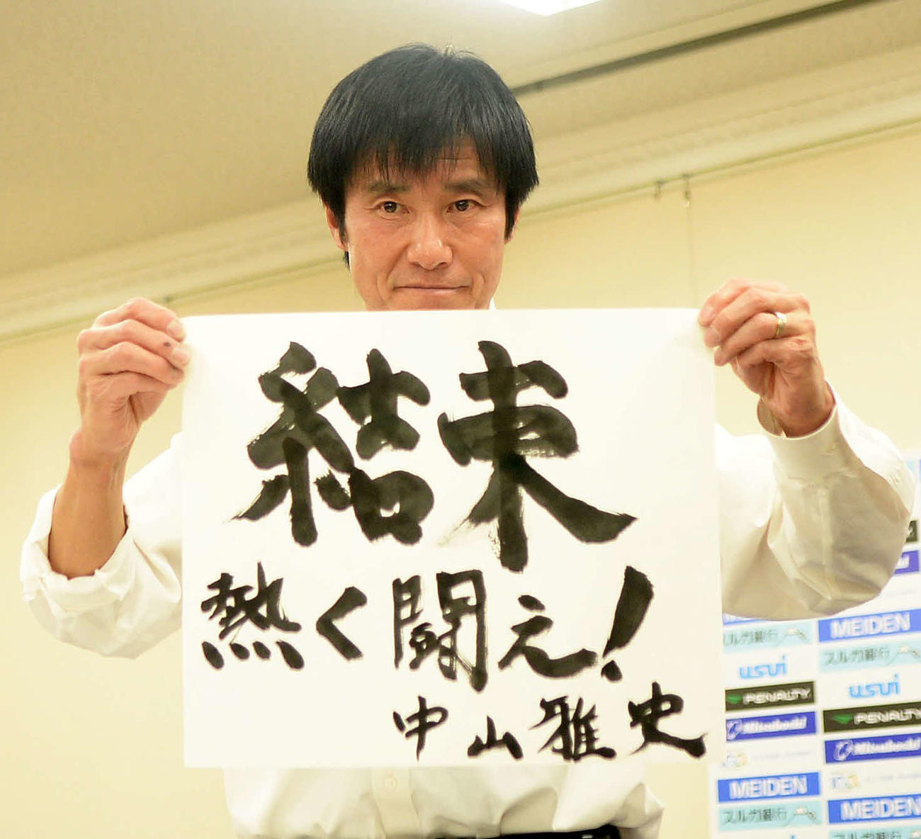 直筆で書いた今季のクラブスローガンを披露するJ3沼津の中山監督