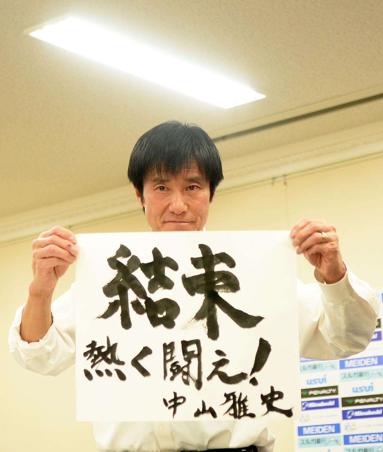 半紙に直筆で書いた今季のクラブスローガンを披露する沼津の中山監督