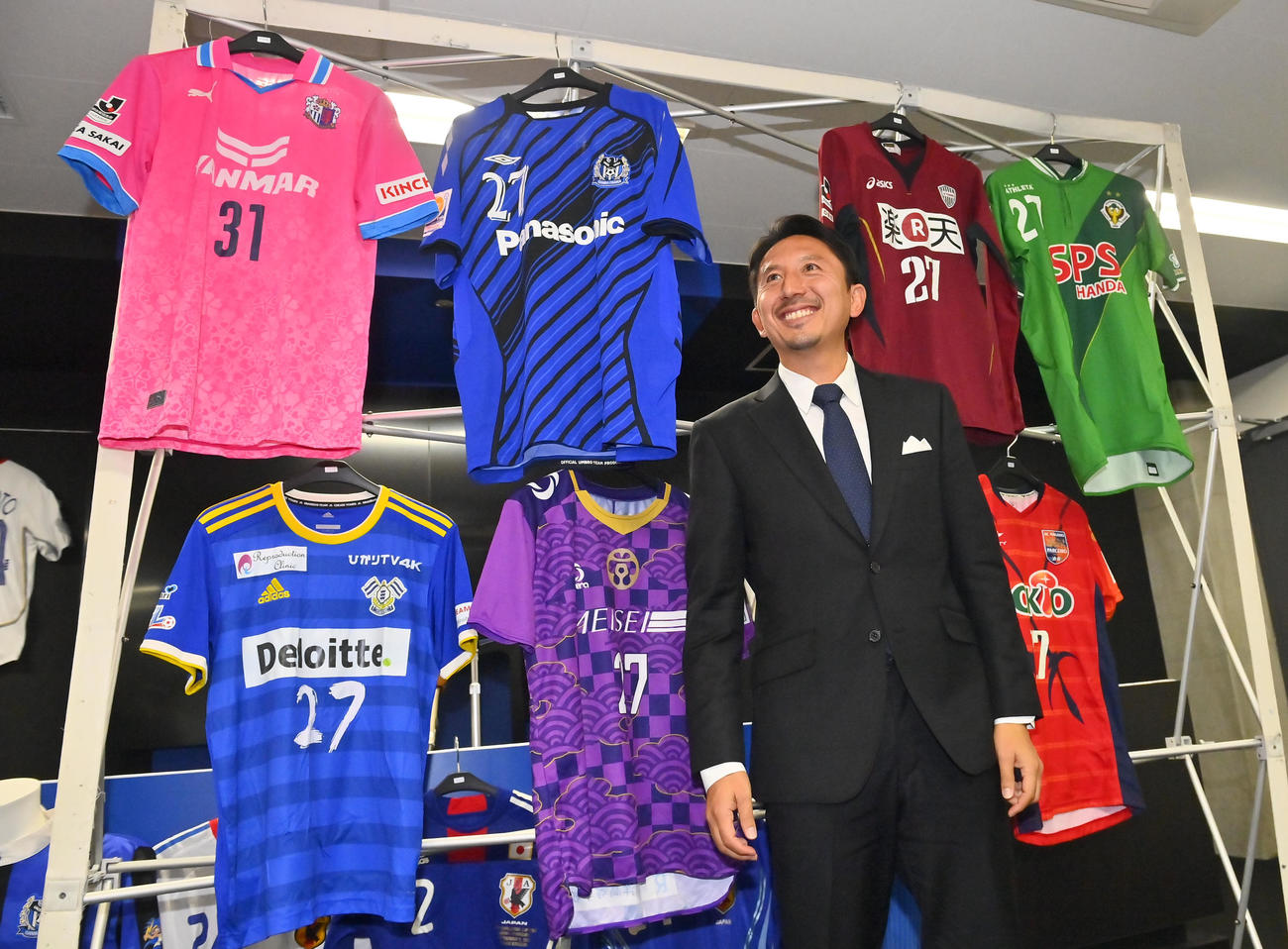 引退会見を行い、所属したユニホームを背に笑顔を見せる橋本（撮影・和賀正仁）
