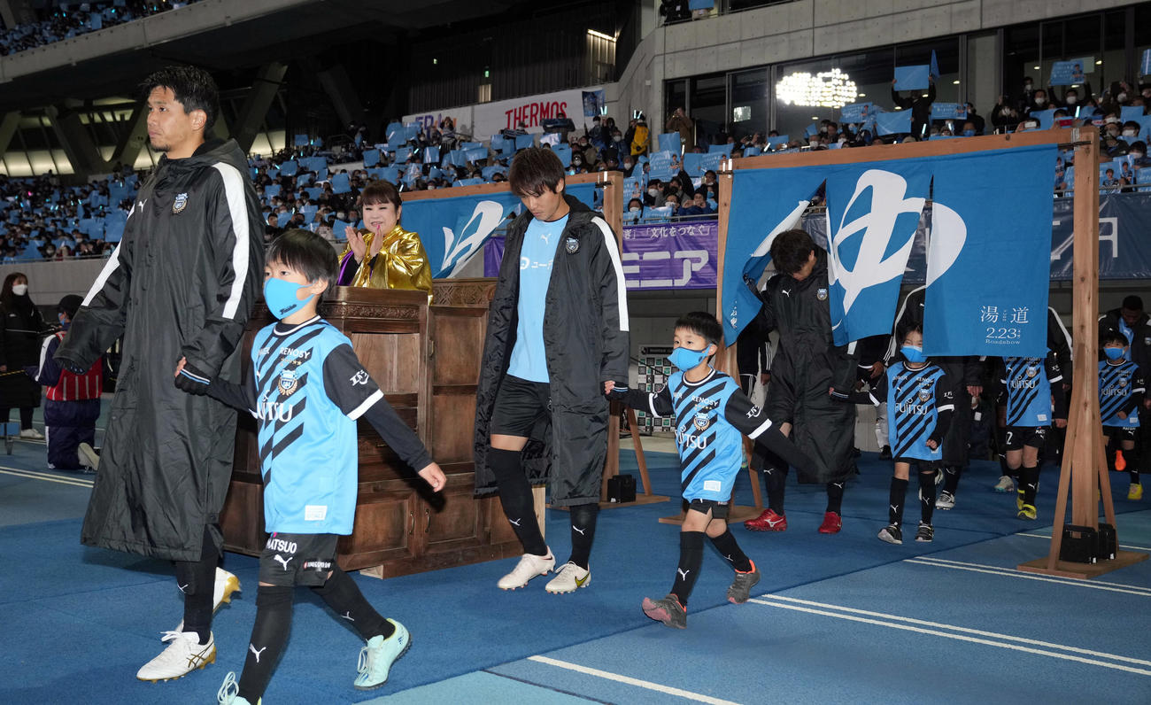川崎F対横浜　試合前、銭湯のような入口から入場する選手たち。番頭を務めるのは天童よしみ（後方左）（撮影・狩俣裕三）