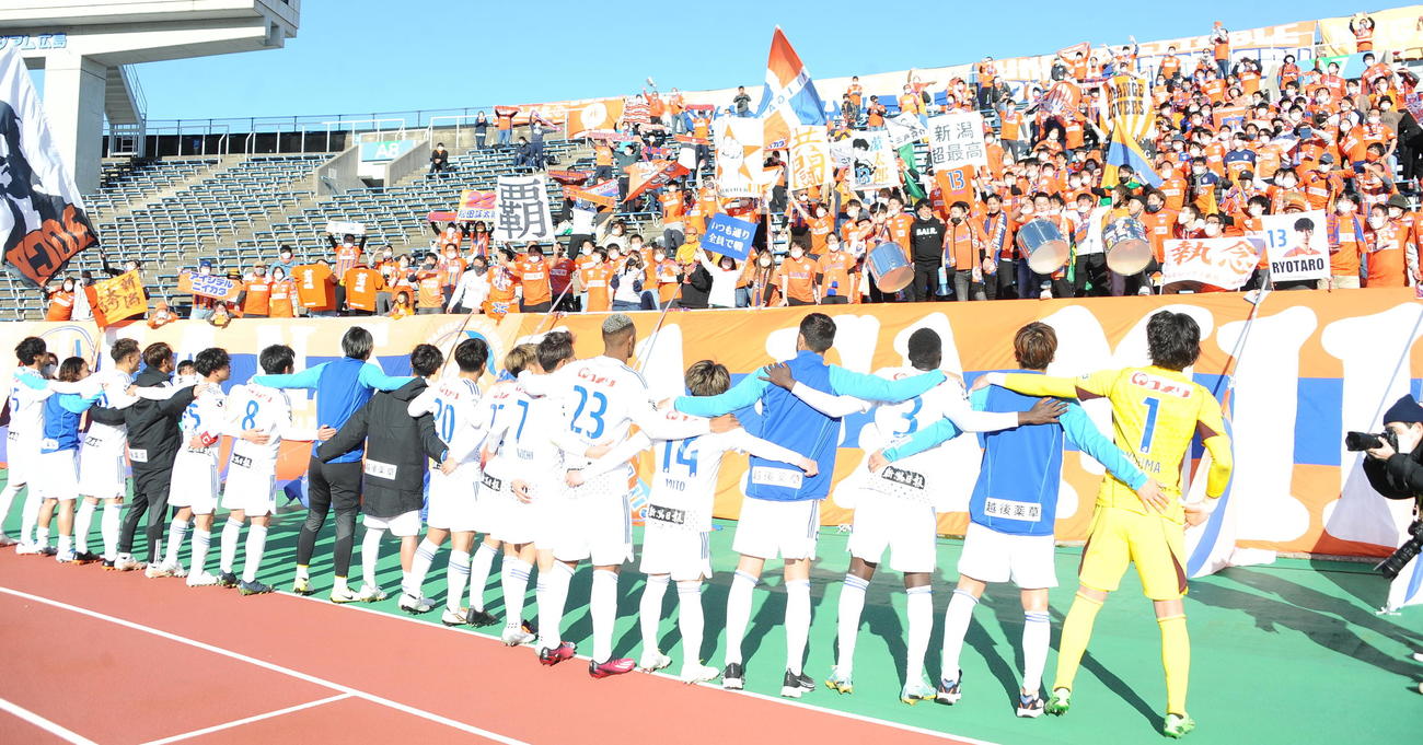 アウェーでJ1復帰後初勝利をつかみ、サポーターと喜び合う新潟の選手たち