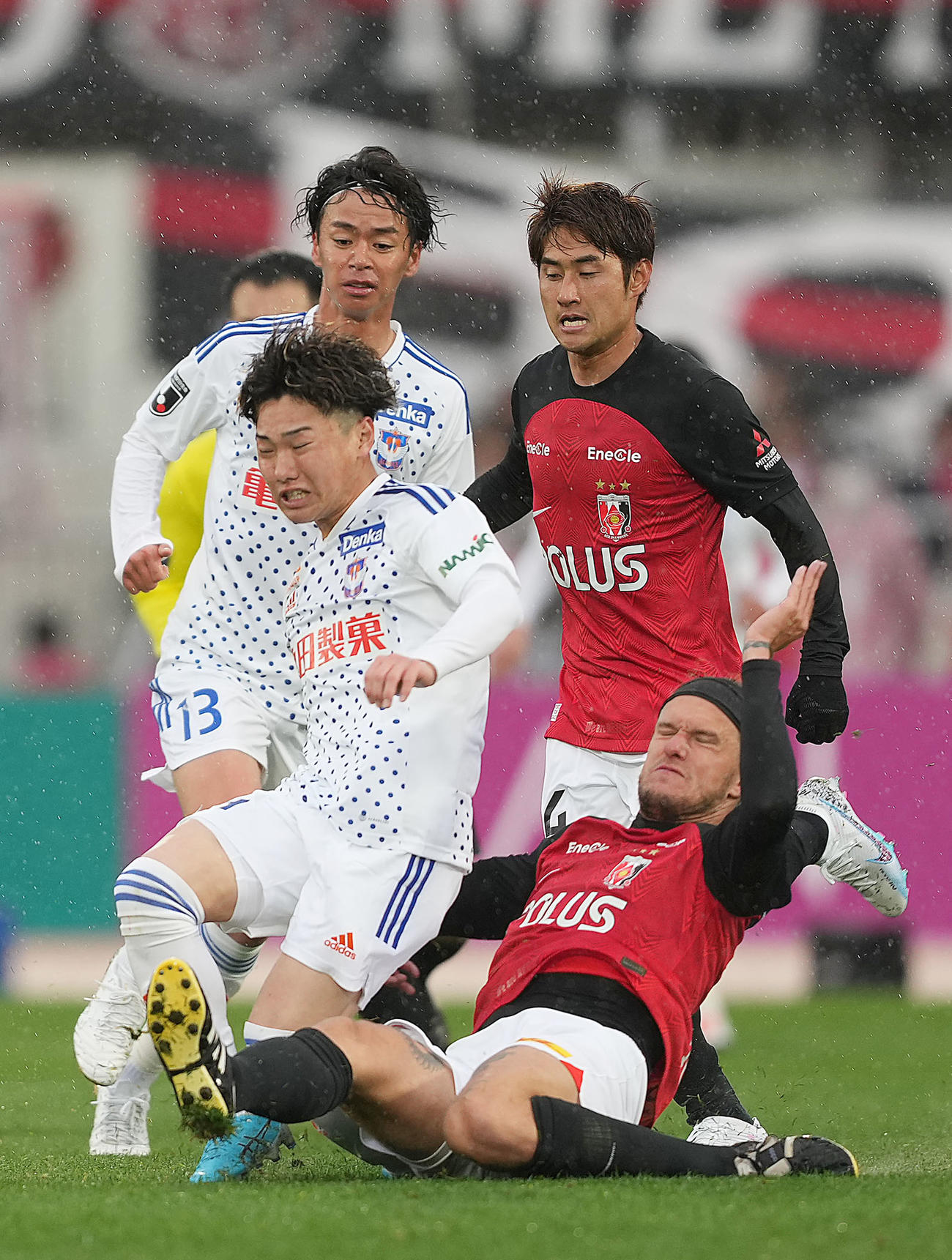 浦和対新潟　後半、浦和ショルツ（手前右）に激しいタックルを食らう新潟三戸（撮影・狩俣裕三）