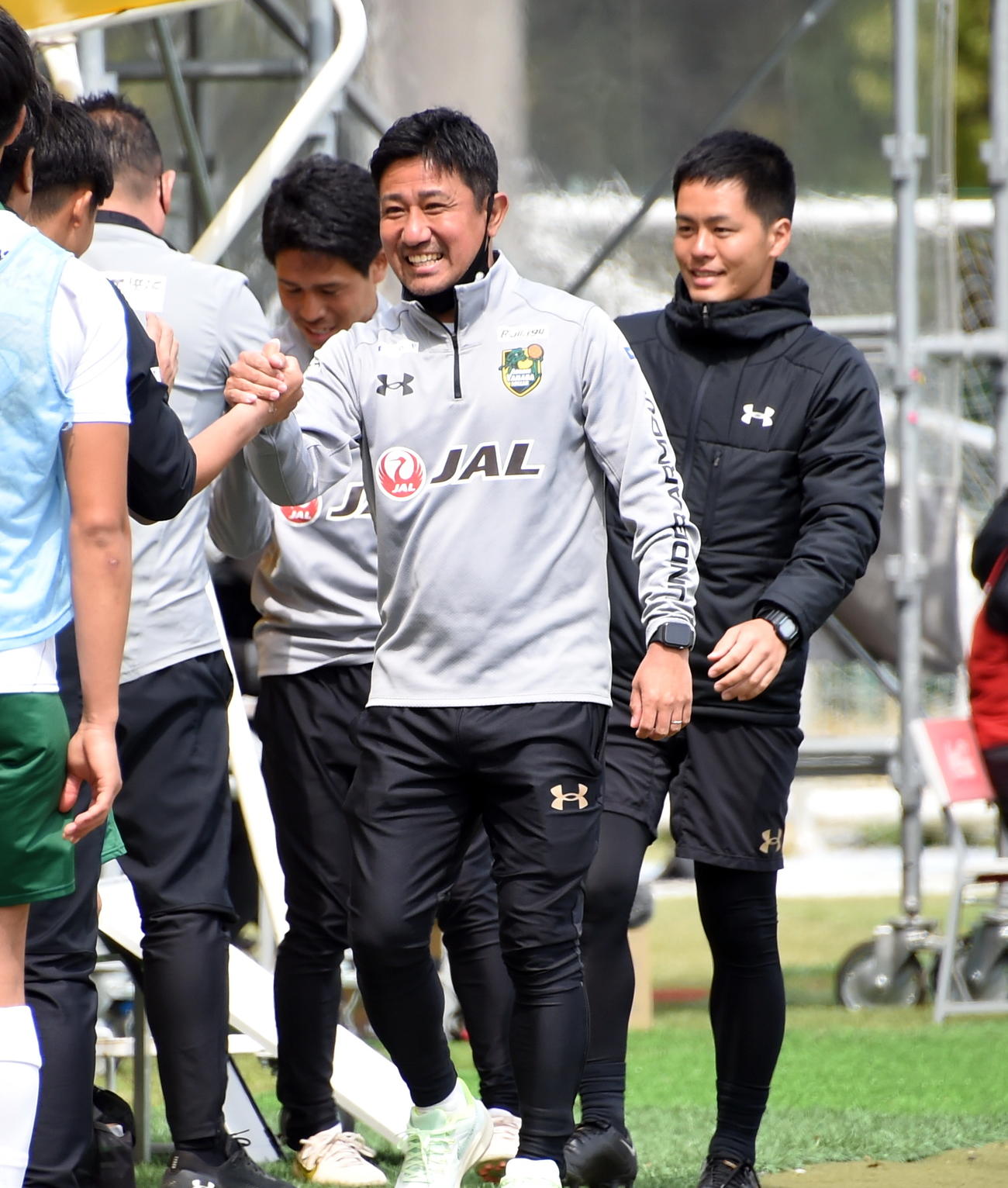 開幕戦に快勝し、笑顔でスタッフと握手をかわす正木監督（中央）