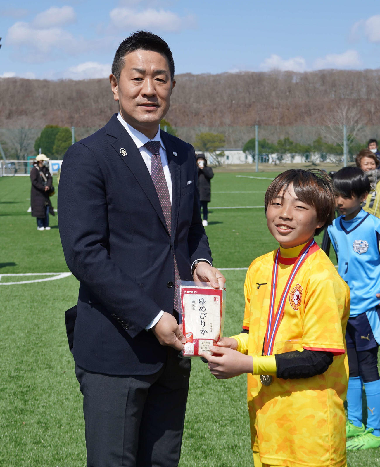優勝チームに副賞の「ゆめぴりか」を手渡すJA全農の山口次長（左）