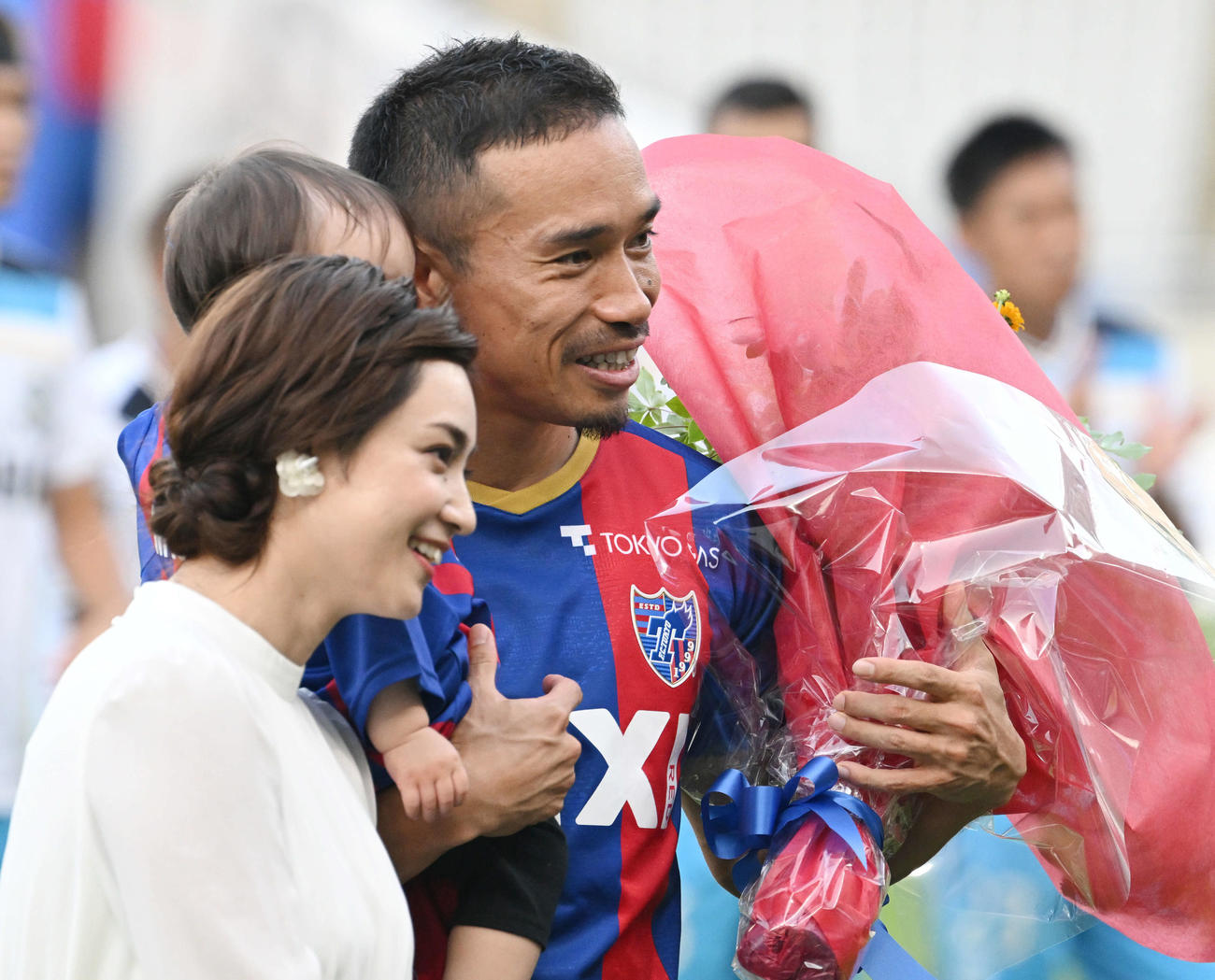 2022年7月、J1通算100試合を達成した東京長友（奥）は妻の平愛梨（手前）ら家族から花束を受け取る