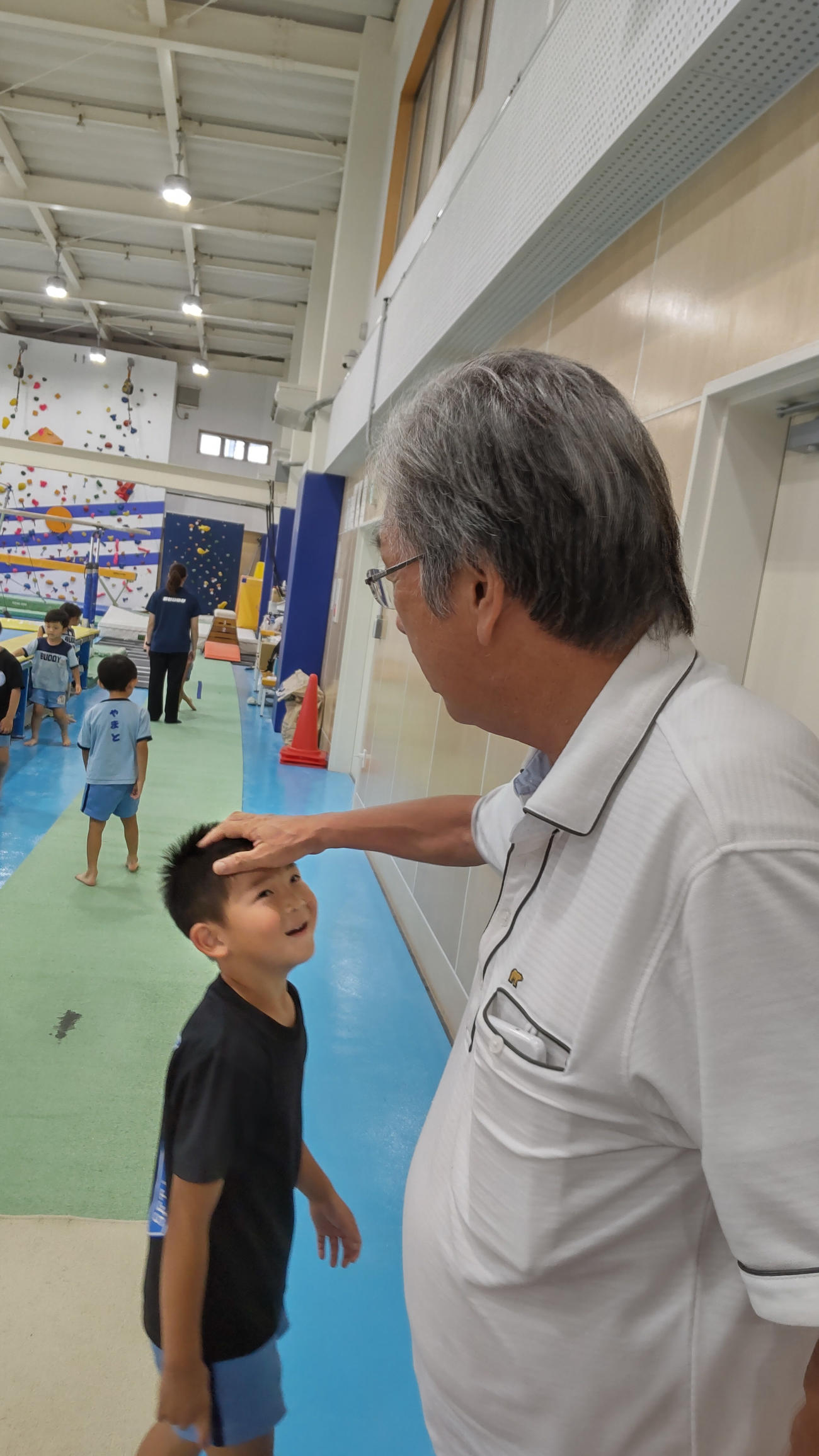 バディスポーツ幼児園の体操室で園児の頭をなでる鈴木威代表