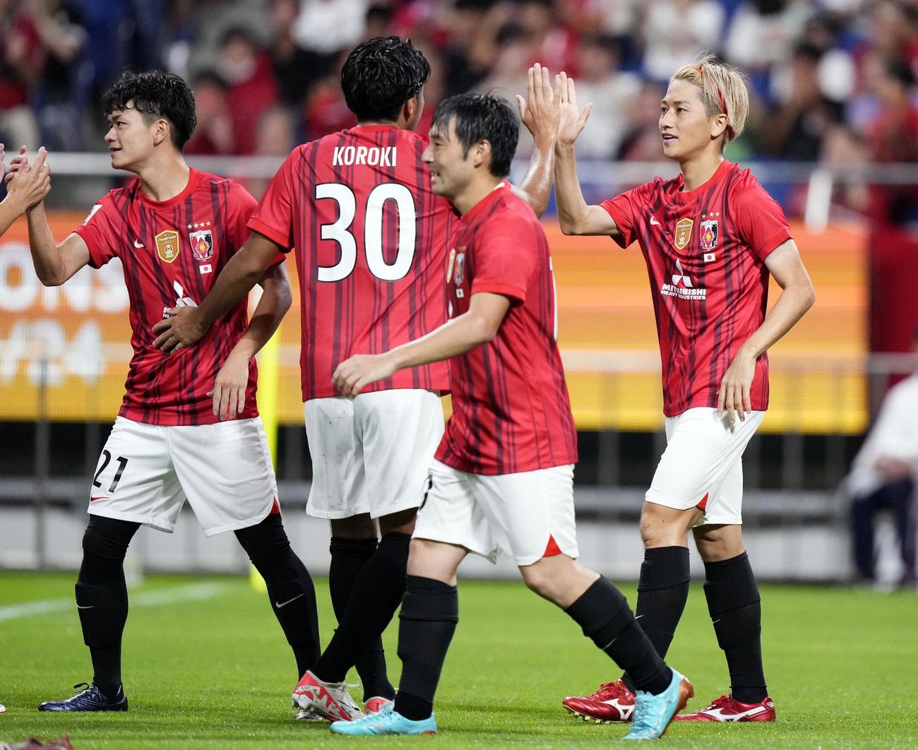 前半、先制ゴールを決め、タッチを交わす浦和・小泉（右端）（共同）