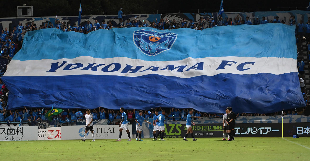 横浜FC対横浜　勝利した横浜FCの選手たちはサポーターにビッグフラッグで祝福される（撮影・山崎安昭）