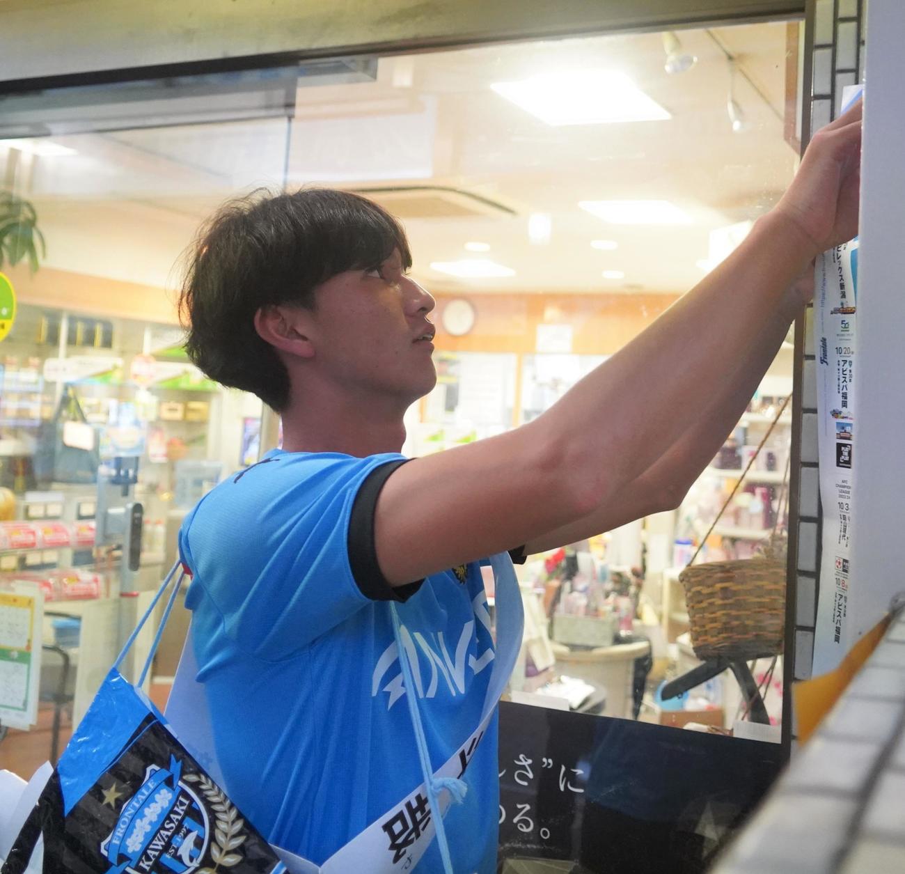 川崎フロンターレの新人研修でポスターを張る名願斗哉（撮影・佐藤成）