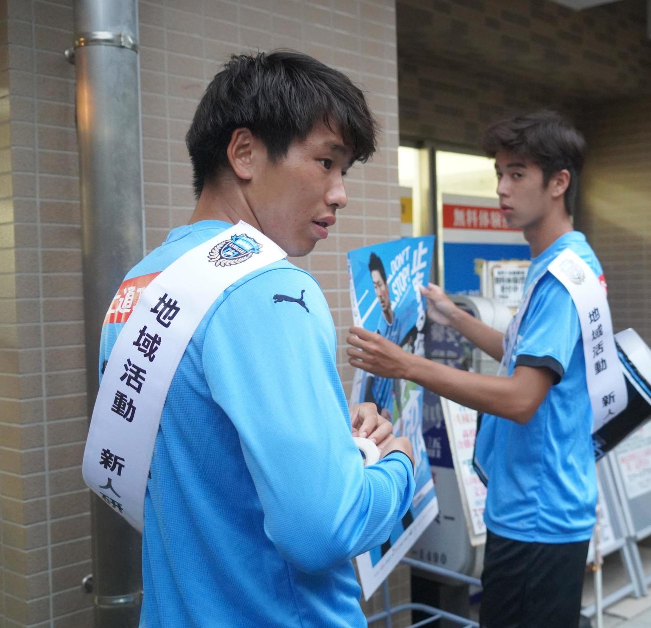 川崎フロンターレの新人研修でポスターを張る山田新（左）と大関友翔（撮影・佐藤成）