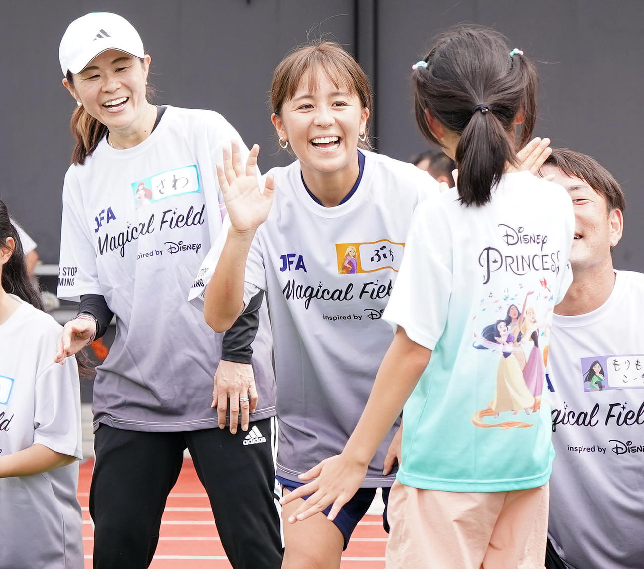 ファミリーサッカーフェスティバルで子どもたちとタッチを交わす岩渕さん（中央）と澤さん（撮影・狩俣裕三）