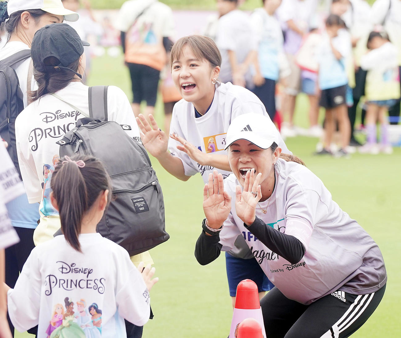 ファミリーサッカーフェスティバルで子どもたちとタッチを交わす澤さん（右）と岩渕さん（撮影・狩俣裕三）