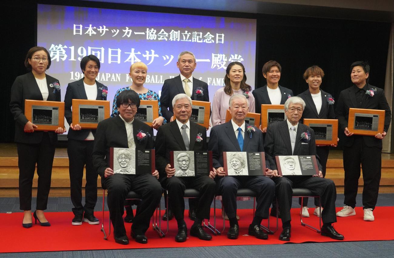 第19回日本サッカー殿堂掲額式典に出席した、前列左から高橋陽一氏、大仁邦弥氏、セルジオ越後氏、大澤英雄氏。後列左から、2011年W杯優勝なでしこジャパンメンバーの山郷のぞみ、近賀ゆかり、丸山桂里奈、佐々木則夫氏、澤穂希、福元美穂、岩清水梓、海堀あゆみ（撮影・佐藤成）