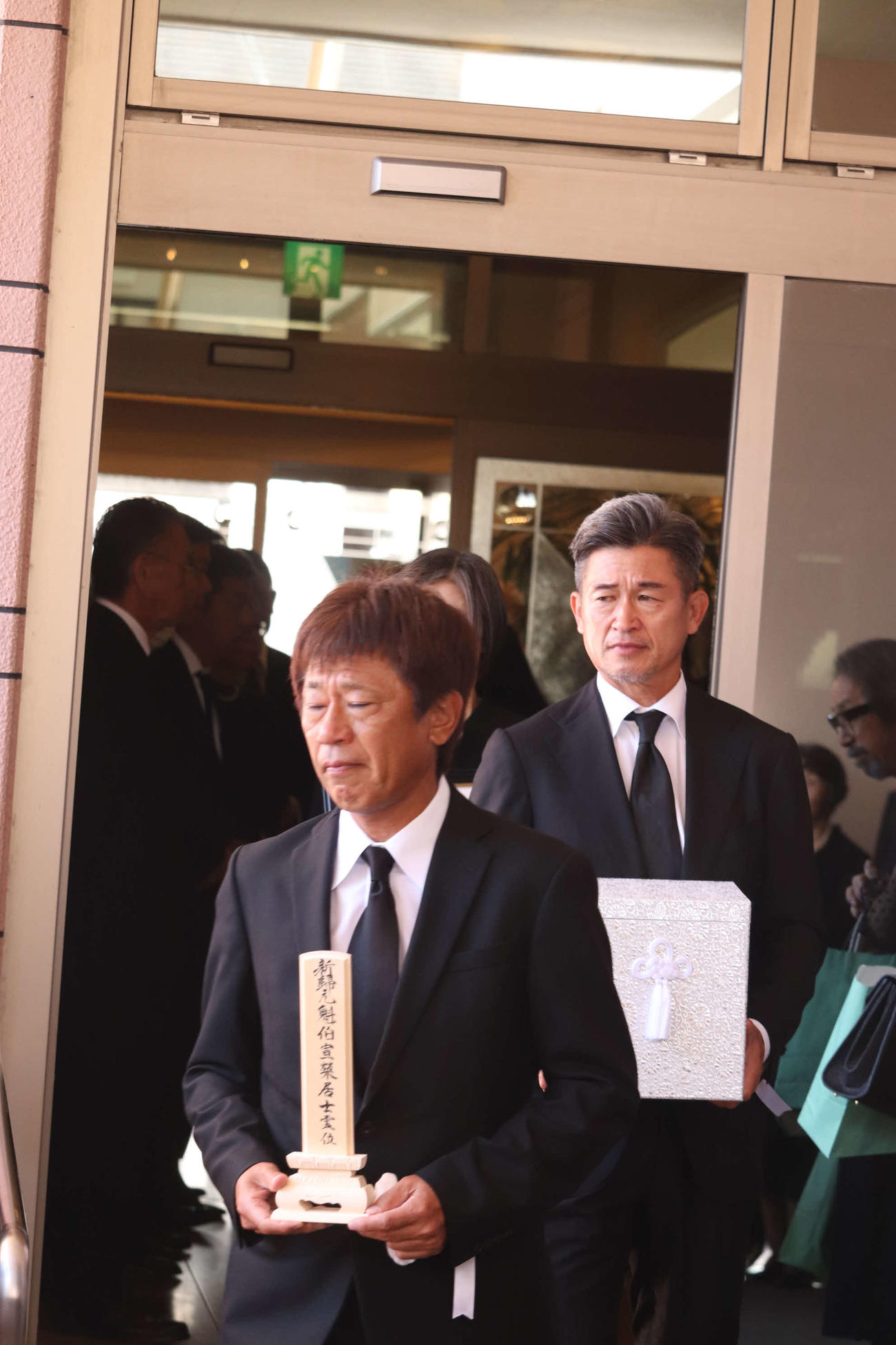 父の納谷宣雄さんを見送る三浦泰年氏（左）とカズ