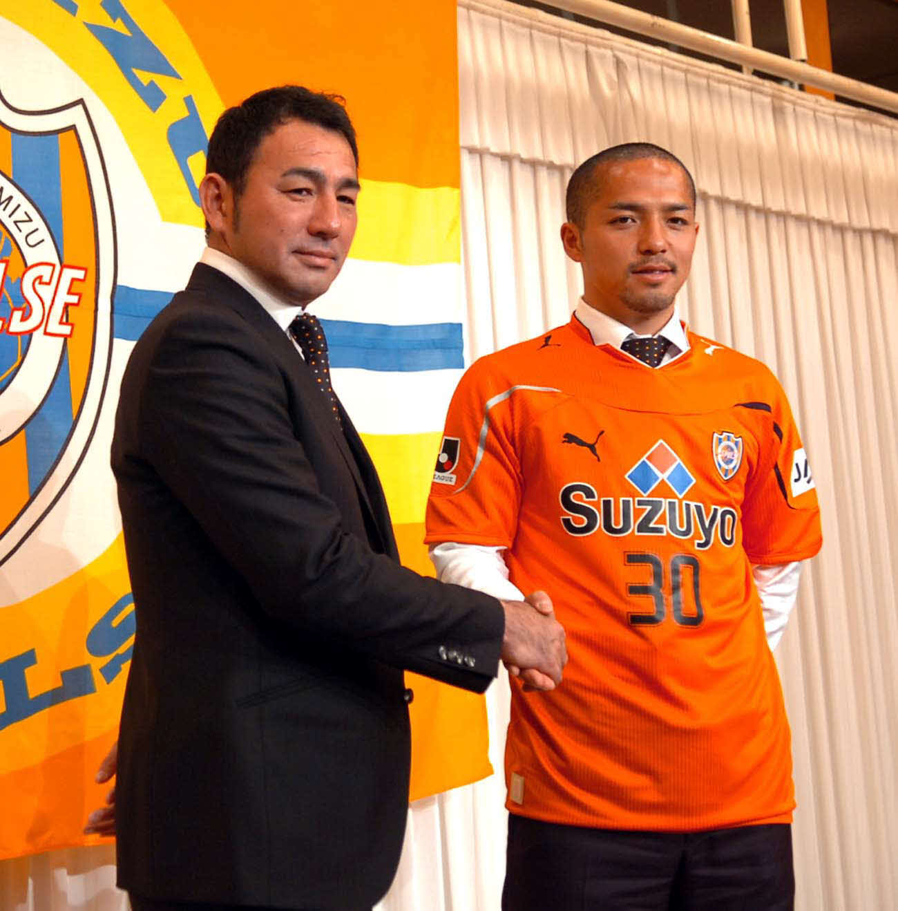 2010年1月22日、清水新入団選手発表　背番号30のユニホームを着て、長谷川健太監督（左）と握手するMF小野伸二