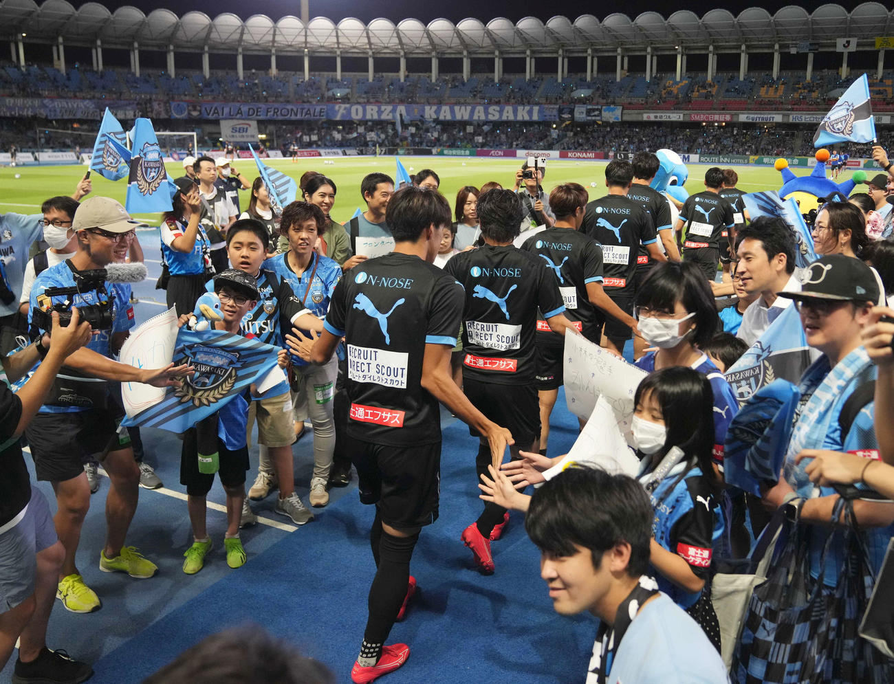 川崎F対新潟　試合前、「えがお共創プロジェクト」の取り組みで、ウオーミングアップに出る川崎Fの選手を出迎える発達障がいのある小学生と家族たち（撮影・狩俣裕三）