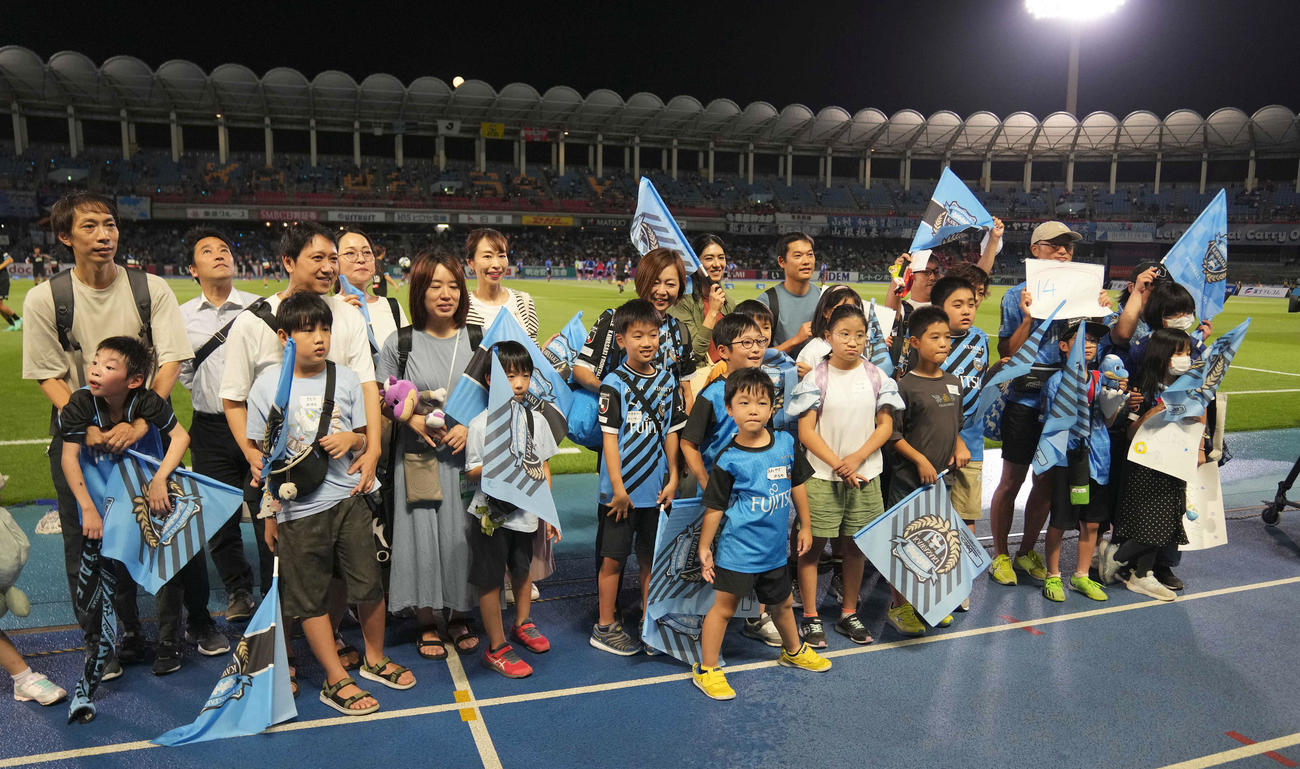 川崎F対新潟　試合前、「えがお共創プロジェクト」の取り組みで、ピッチ前で記念撮影をする発達障がいのある小学生と家族たち（撮影・狩俣裕三）