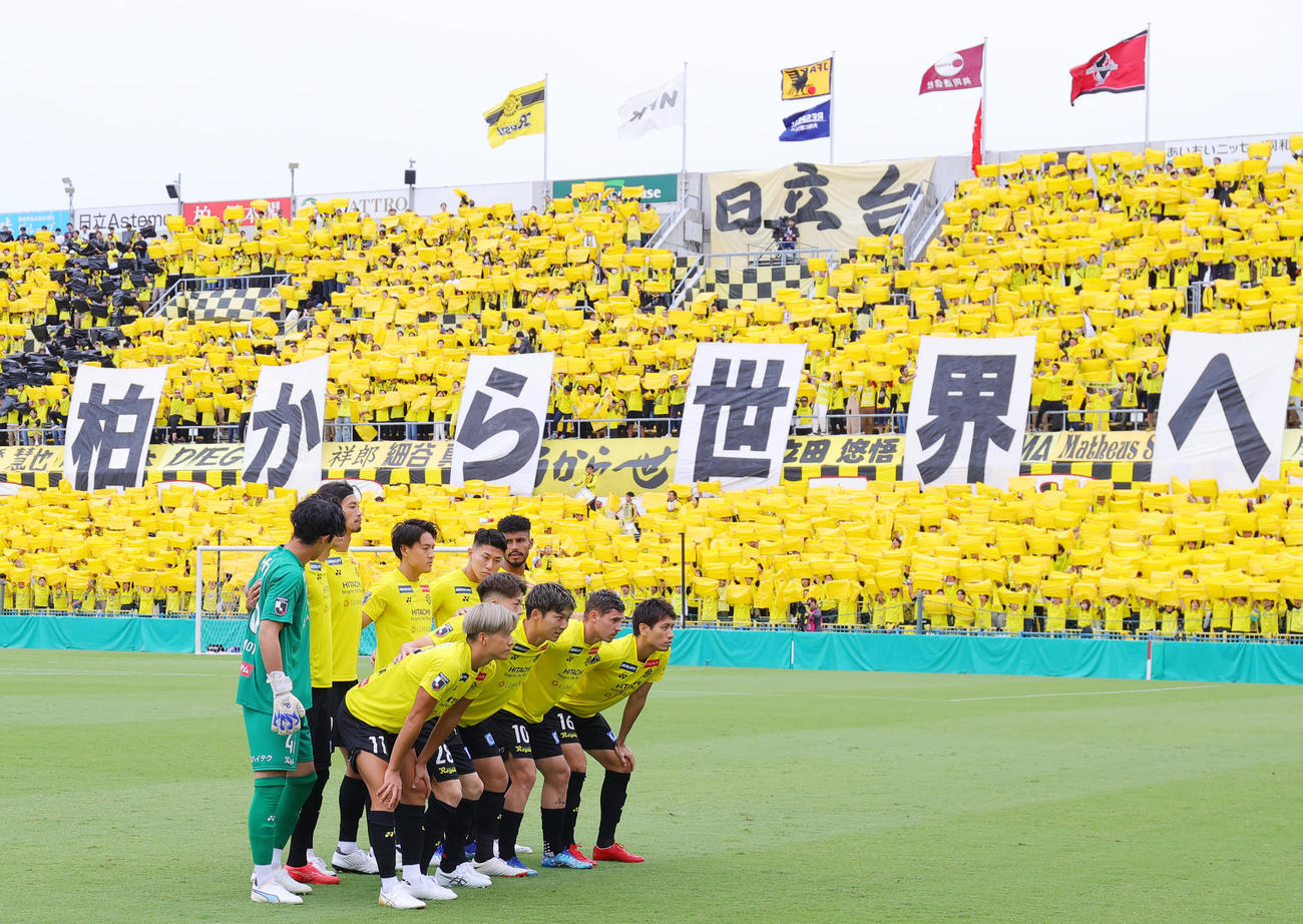 熊本対柏　試合前に「柏から世界へ」のボードが出る中、集合写真に納まる柏イレブン（撮影・野上伸悟）