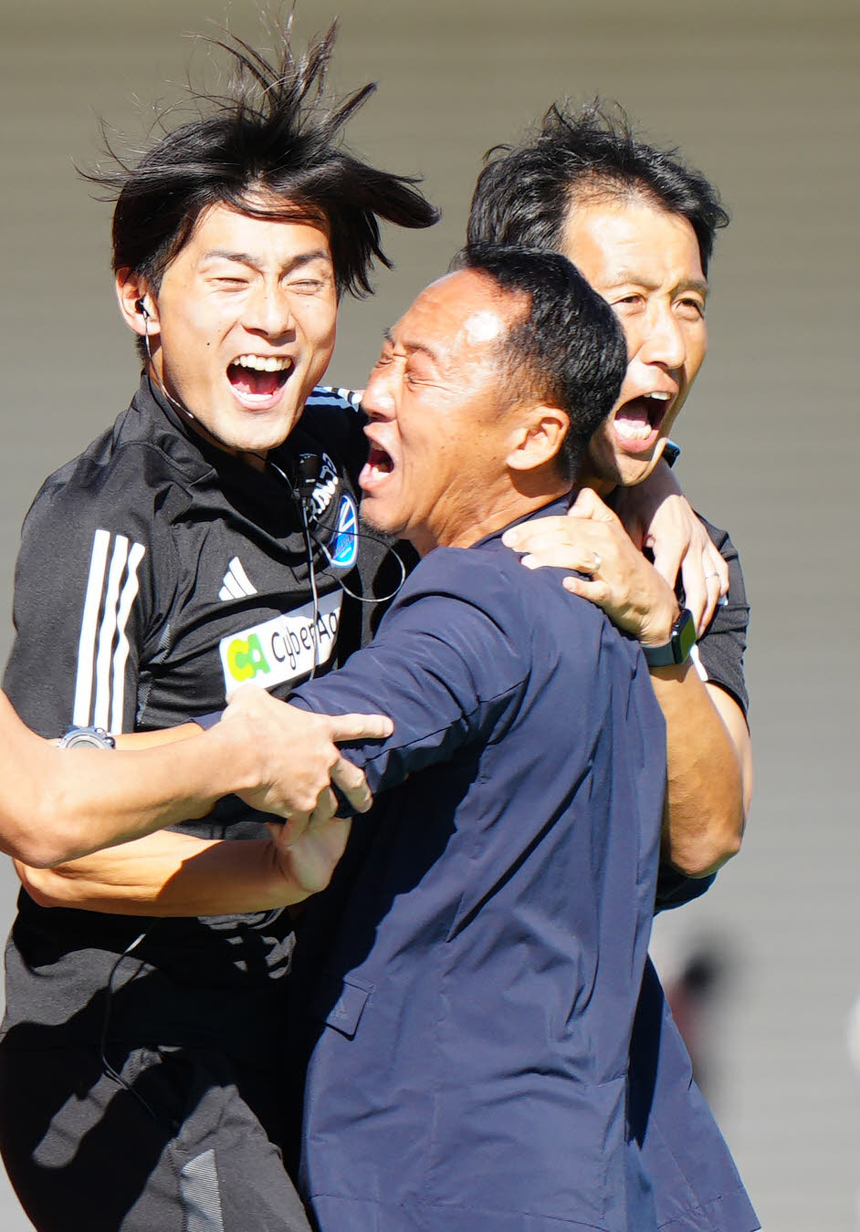 熊本対町田　後半、町田高橋大がチーム2点目となるゴールを決め、歓喜する山中コーチ（左）の顔が当たった黒田監督。右は金ヘッドコーチ（撮影・江口和貴）