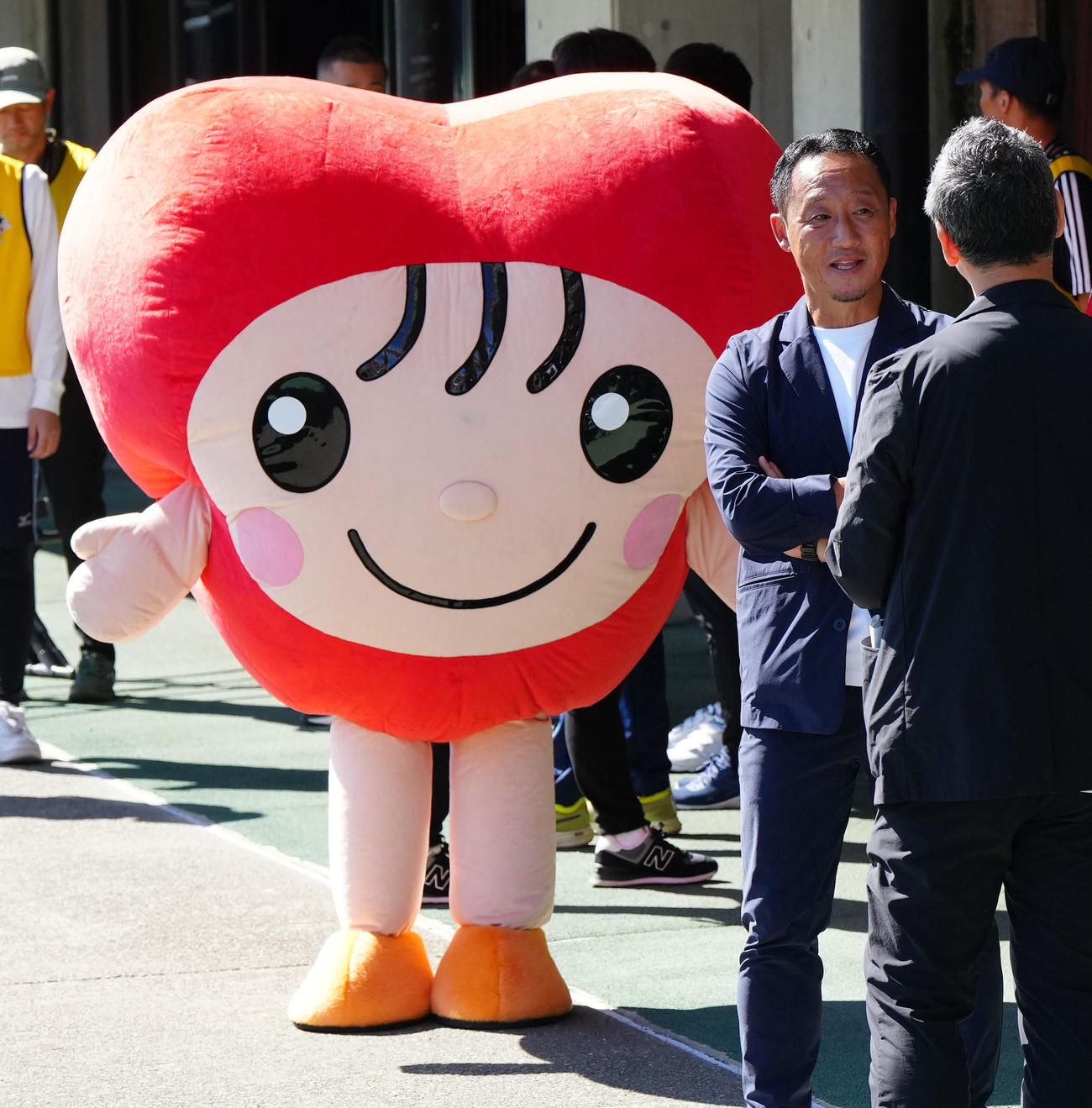 試合前、関係者と話す町田黒田監督。左は熊本市人権啓発市民協議会の人権啓発キャラクターのラブミン（撮影・江口和貴）