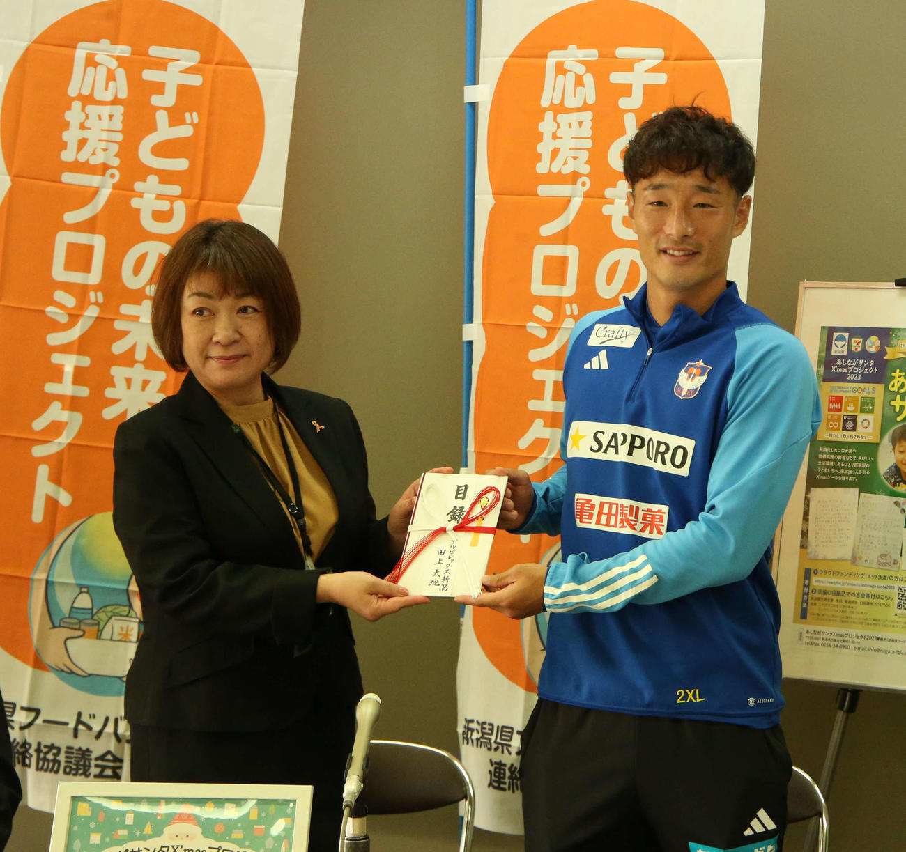 野菜販売の寄付金目録を県フードバンク連絡協議会の山下会長（左）に手渡す新潟田上