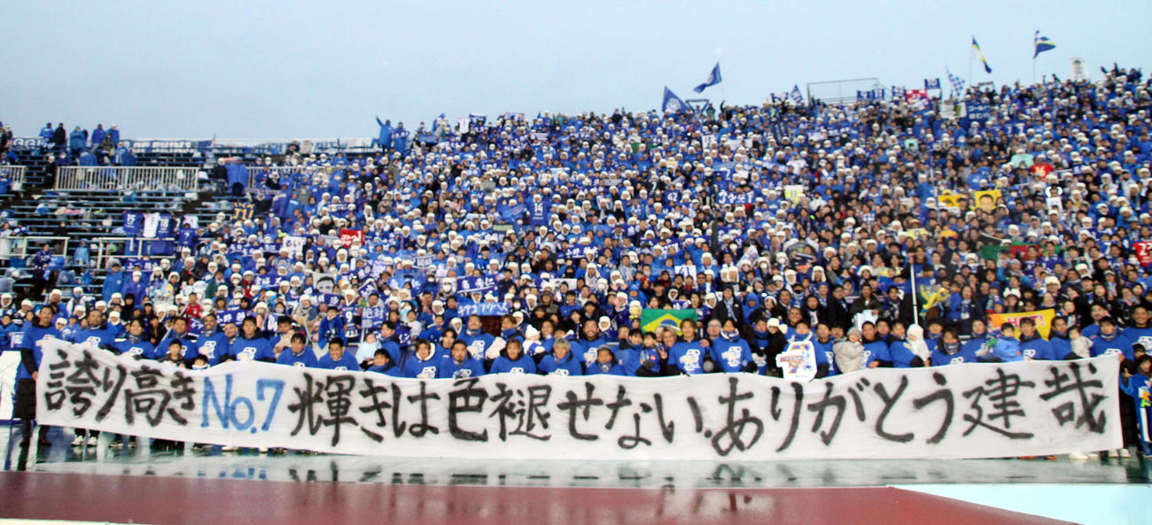 今シーズン限りで引退する岡崎建哉の横断幕を持って、サポーターとともに記念撮影する山形イレブン