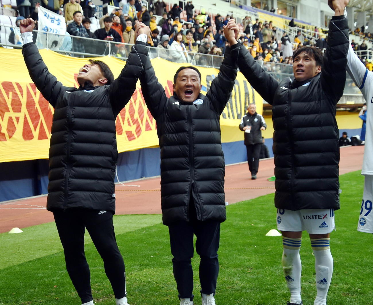 最終戦を勝利で飾り、両手を上げてサポーターと喜びを分かち合う町田黒田監督（中央）