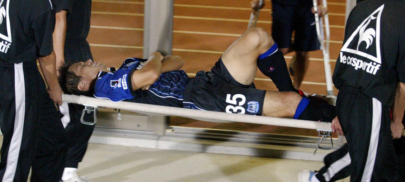 G大阪対横浜　後半早々、ドゥトラと接触した際、右ヒザを痛めたDF宮本恒靖はタンカで退場（2002年8月撮影）