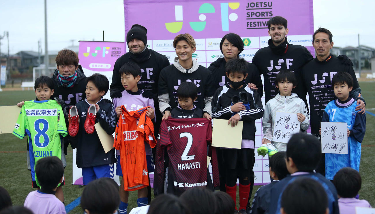 ジャンケンで獲得したプレゼントに喜ぶ子どもたちとJリーガー6人、後段左からFW鈴木（新潟）、DF舞行龍（同）、MF飯野（神戸）、MF森谷（鳥栖）、MF長谷川（鳥取）、DF武田（横浜FC）