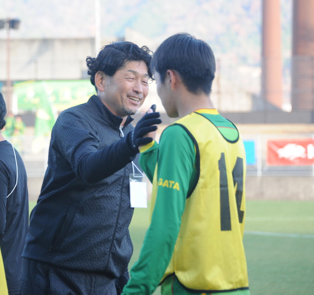 プレミアリーグ初昇格を決めた帝京長岡の谷口総監督（左）が堀主将とタッチ