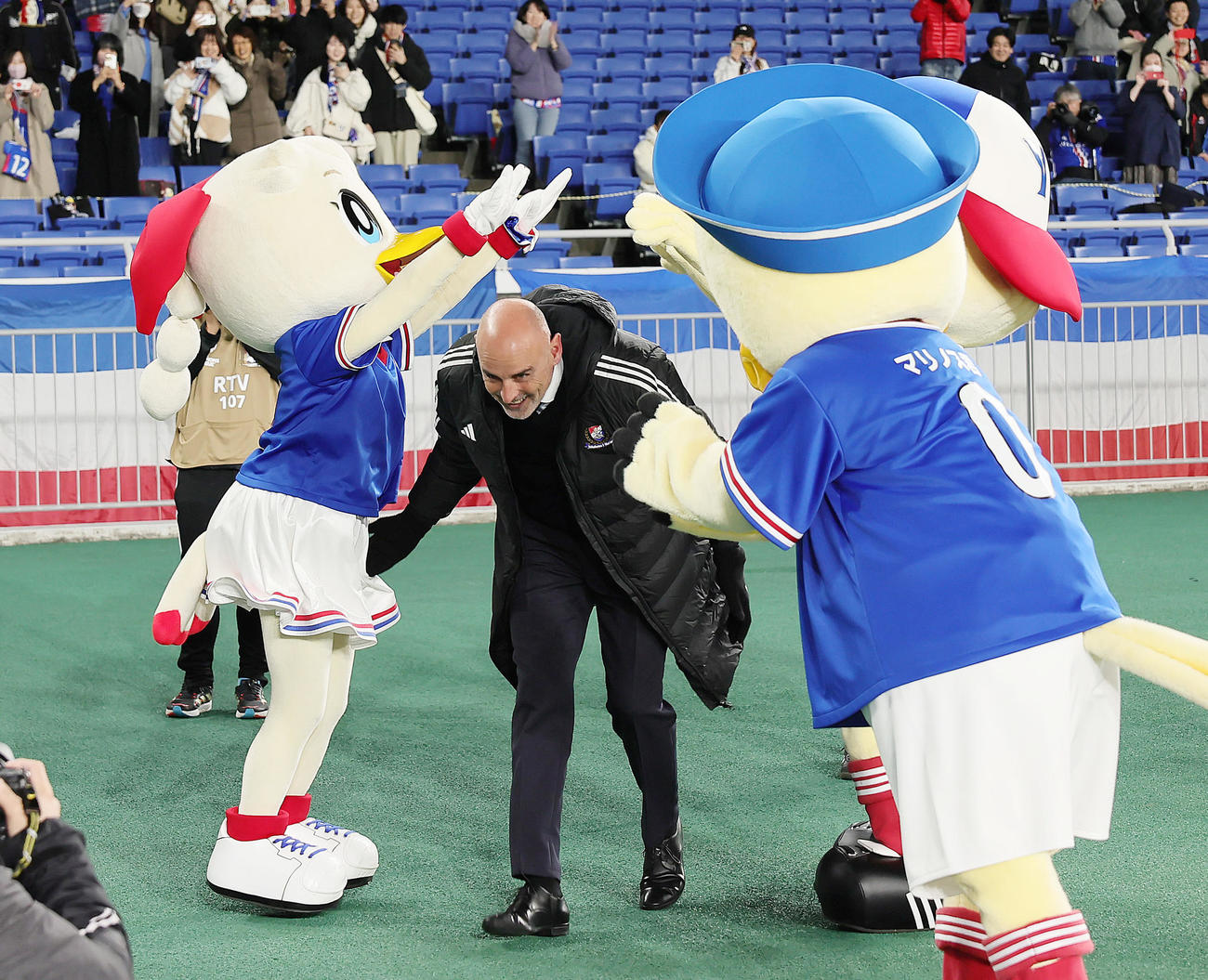 横浜対山東泰山　今季で退任が決まっている横浜マスカット監督はマスコットの作った花道を笑顔でくぐり抜ける（撮影・足立雅史）