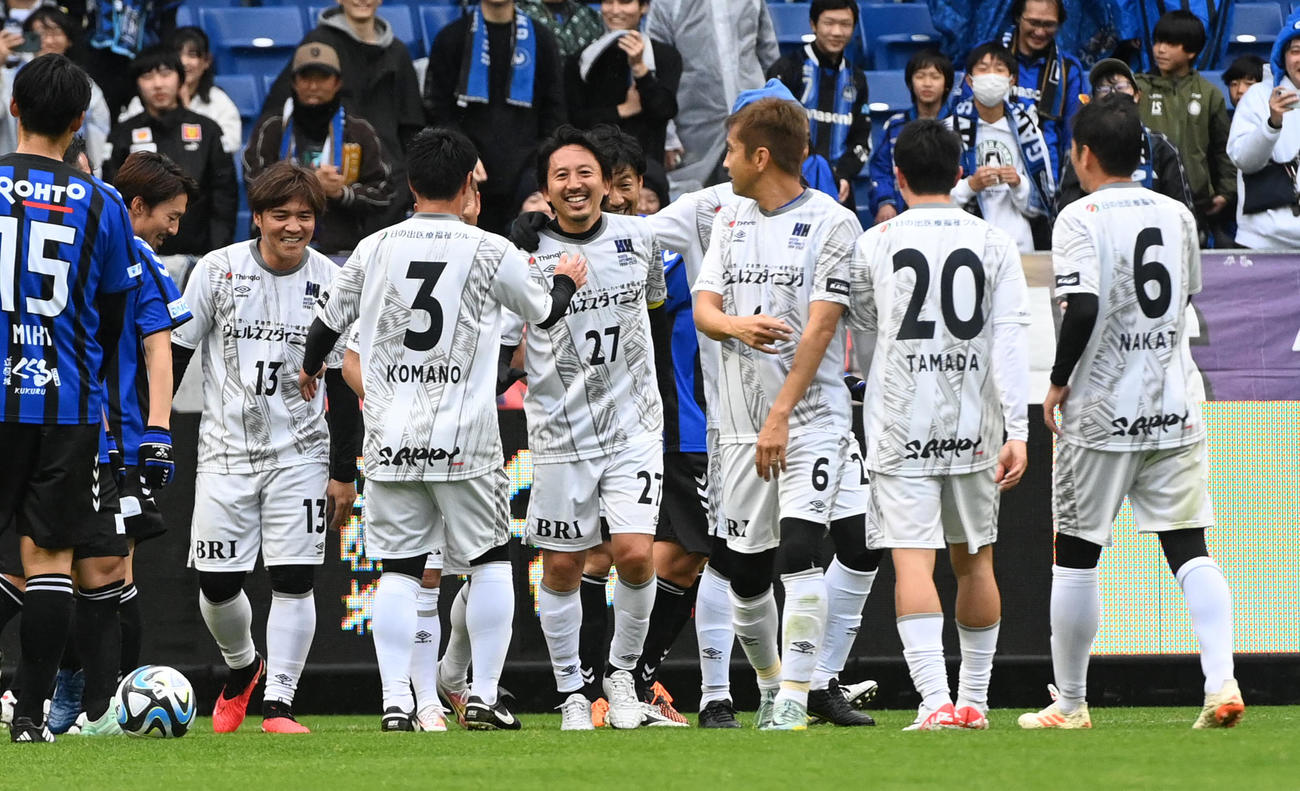 ガンバ大阪’05対日本代表フレンズ　前半、先制ゴールを決めた日本代表フレンズ橋本（中央）はイレブンの祝福に笑顔を見せる（撮影・前岡正明）