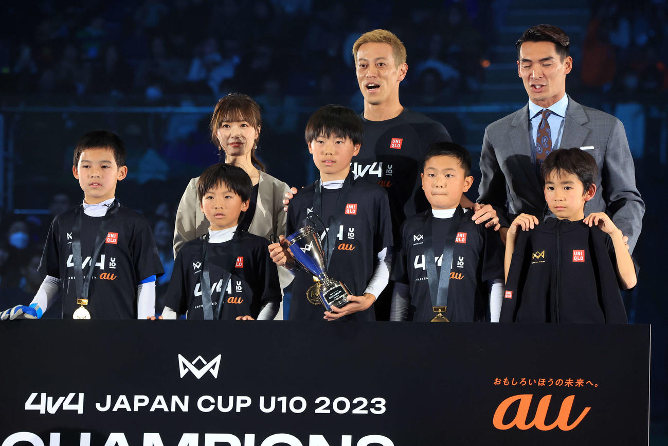 「4v4JAPANCUP U10 2023」で優勝チームと笑顔で記念撮影する本田圭佑（後列中央）。後列右は槙野智章氏（撮影・浅見桂子）