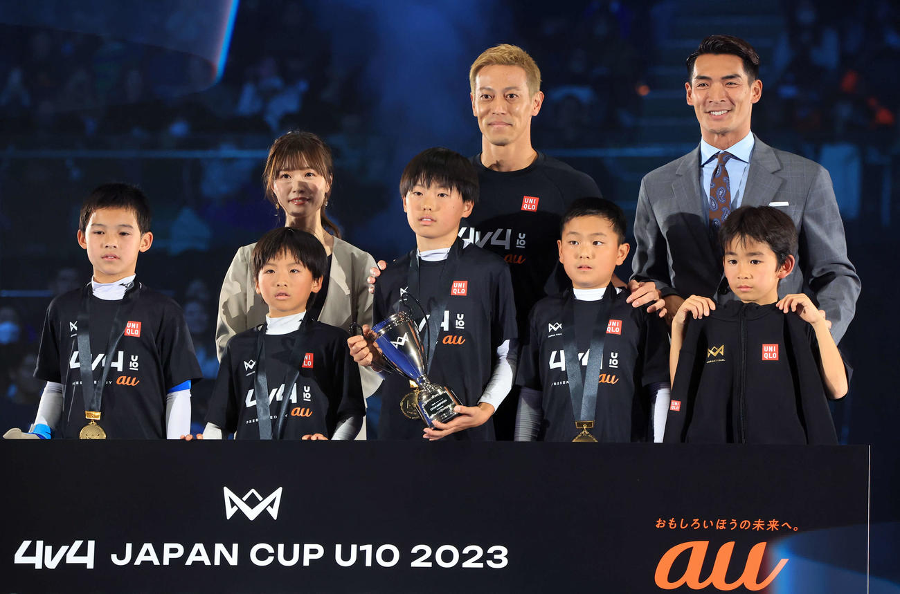 「4v4JAPANCUP U10 2023」で優勝チームと笑顔で記念撮影する本田圭佑（後列中央）。後列右は槙野智章氏（撮影・浅見桂子）