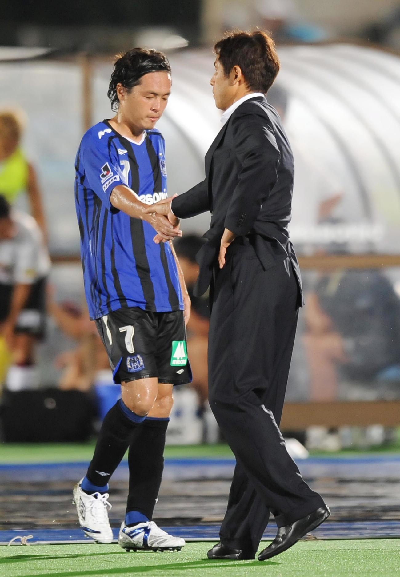 08年8月23日　Jリーグ（J1）・第22節　G大阪対神戸　後半、ベンチに下がるG大阪MF遠藤保仁は西野朗監督と握手を交わす