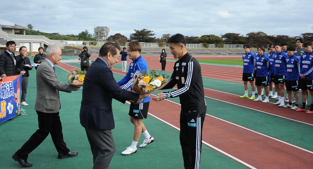 沖縄キャンプの歓迎セレモニーで桑江沖縄市長から花束を受け取る松橋監督（中央）。奥は堀米