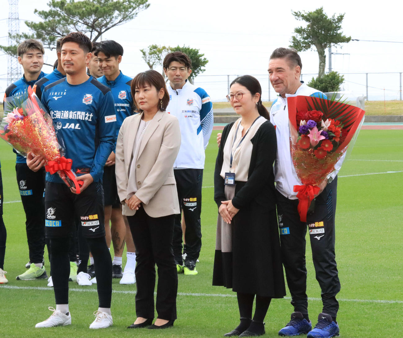 金武町からの歓迎セレモニーで花束を受け取った札幌ペトロビッチ監督（右端）と宮沢（左端）（撮影・保坂果那）