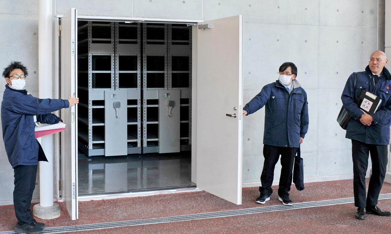 防災備蓄倉庫の可動棚を見せる藤枝市職員　