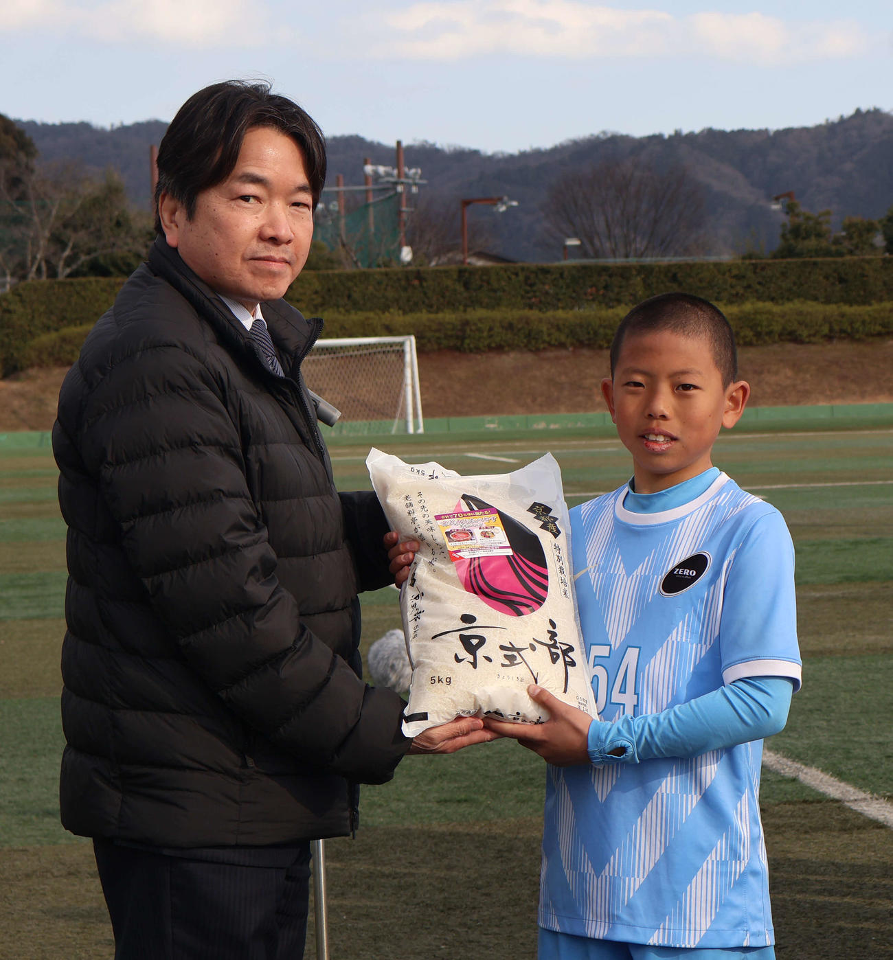 優勝チームに副賞を手渡したJA全農京都の江守孝教管理部長（左）