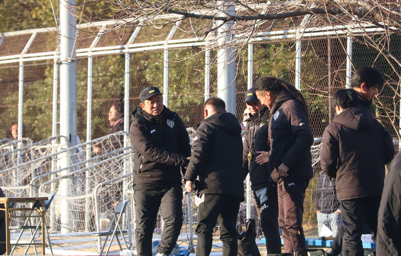 南葛SCの初陣を白星で飾った風間八宏監督（左）はスタッフと握手を交わす