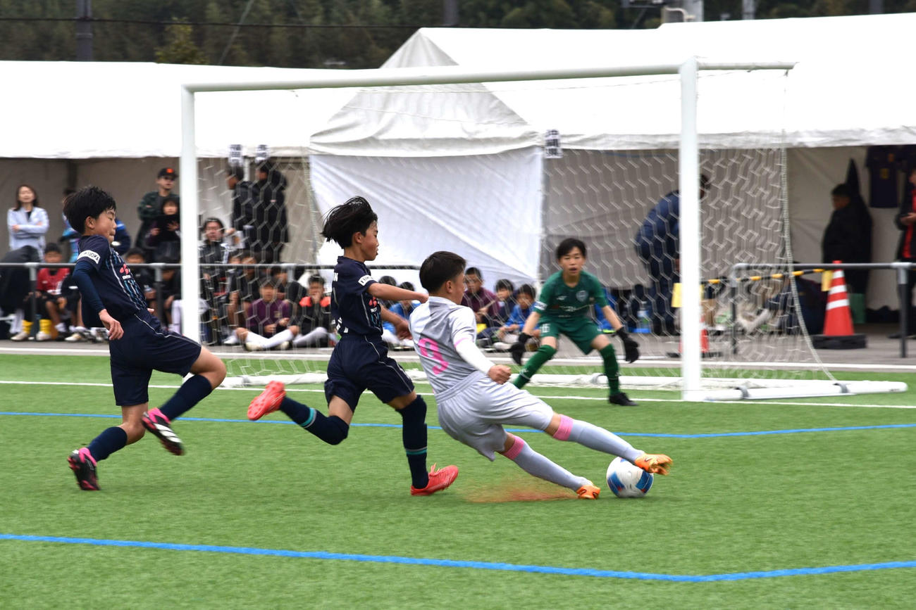 アビスパ福岡U－12戦で、相手のマークを振り切ってスライディングシュートを放つ、壱岐少年サッカークラブの齋藤七音（写真右）