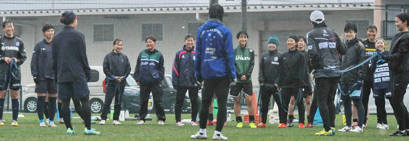 強い雨の中、笑顔でコーチの話を聞く選手たち