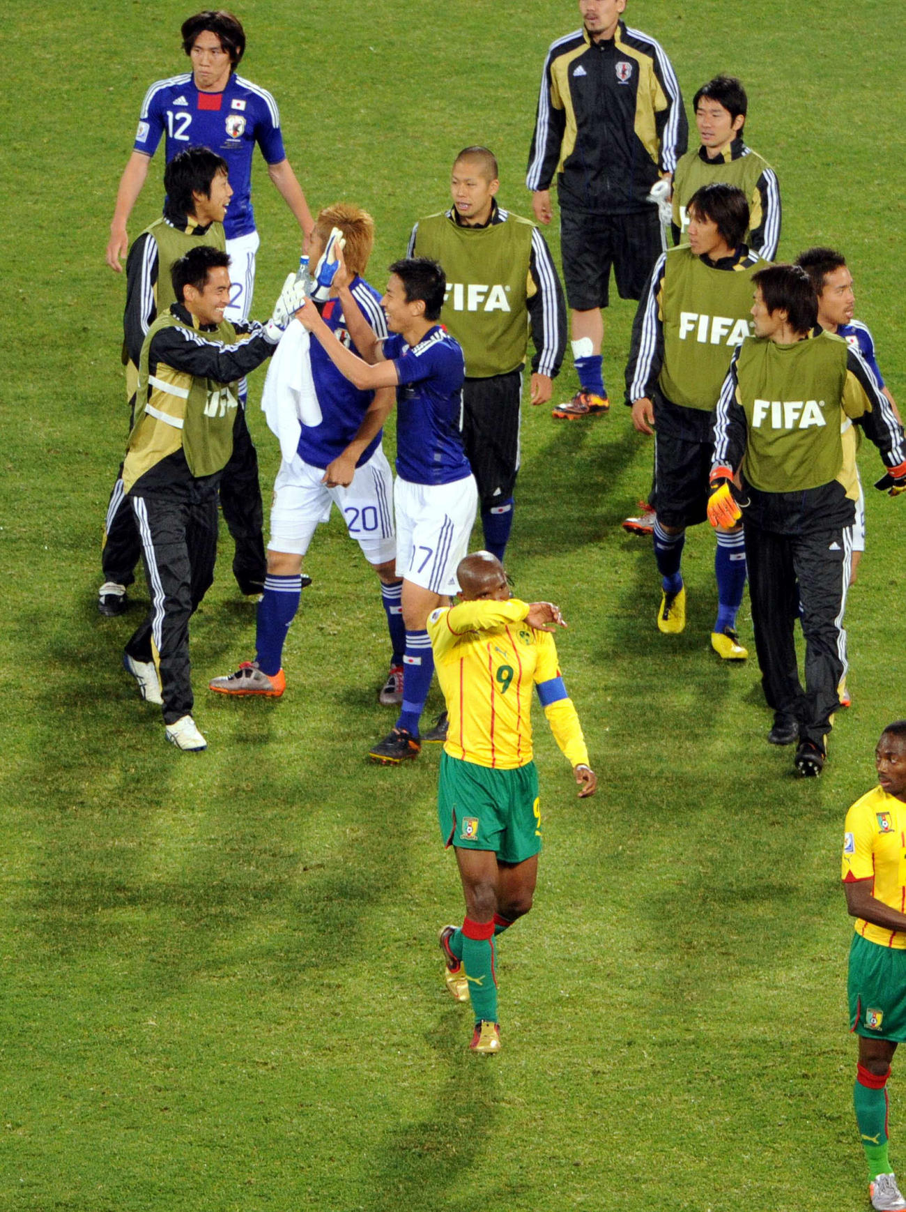 10年6月、W杯南アフリカ大会　日本対カメルーン　汗をぬぐいながらガックリと引き揚げるカメルーンFWサミュエル・エトー。後方は笑顔でハイタッチするMF長谷部誠とGK川口能活